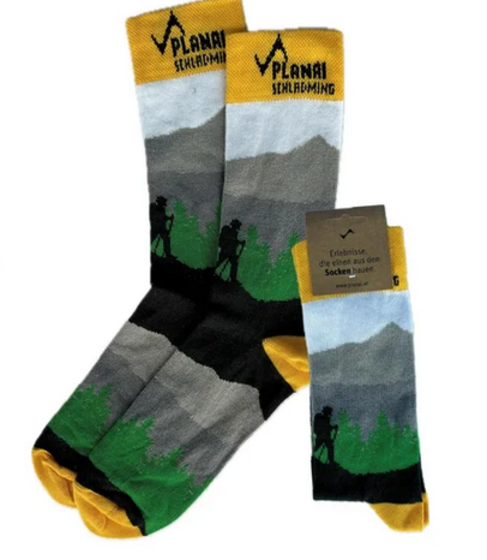 Three pairs of hiking socks with Planai branding, mountain scenery, hikers and green-yellow design | © Planai-Hochwurzen-Bahnen GmbH