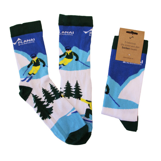 Three pairs of ski socks with Planai branding, skiers, snowy mountains and green pine trees | © Planai-Hochwurzen-Bahnen GmbH