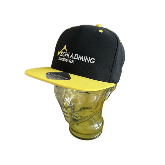 Black snapback cap with yellow brim and Bikepark embroidery shown on glass mannequin head | © Planai-Hochwurzen-Bahnen GmbH