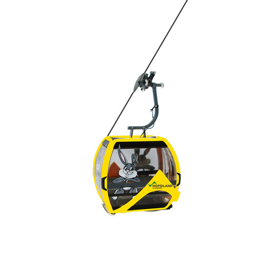 Yellow cable car gondola with bunny graphic and Hopsiland label on the front, suspended in air | © Planai-Hochwurzen-Bahnen GmbH