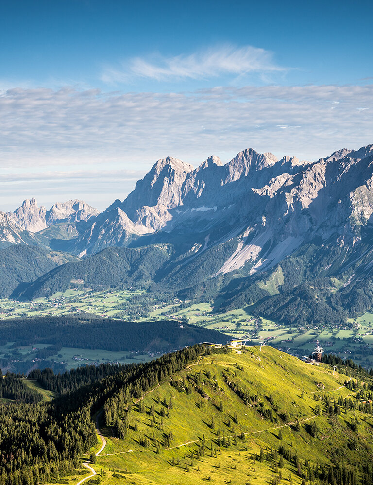 Panoramic view from Krahbergzinken over green ridges, forests and valleys toward the impressive Dachstein south face | © Planai-Hochwurzen-Bahnen GmbH
