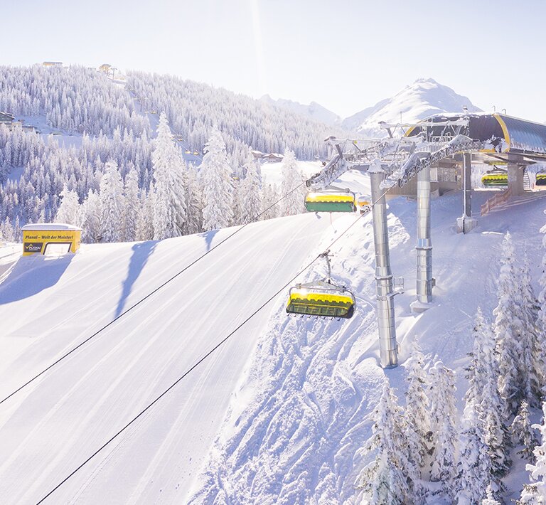 Gelbe Sesselbahn fährt durch verschneite Bäume am sonnigen Lärchenkogel auf der Planai | © Planai-Hochwurzen-Bahnen GmbH